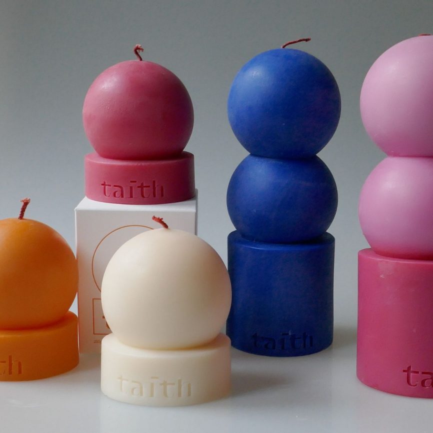 Bunte Designkerzen von Taith in modernen Kugelformen in Rot, Blau, Rosa, Weiß und Orange, arrangiert als dekorative Duftkerzen.