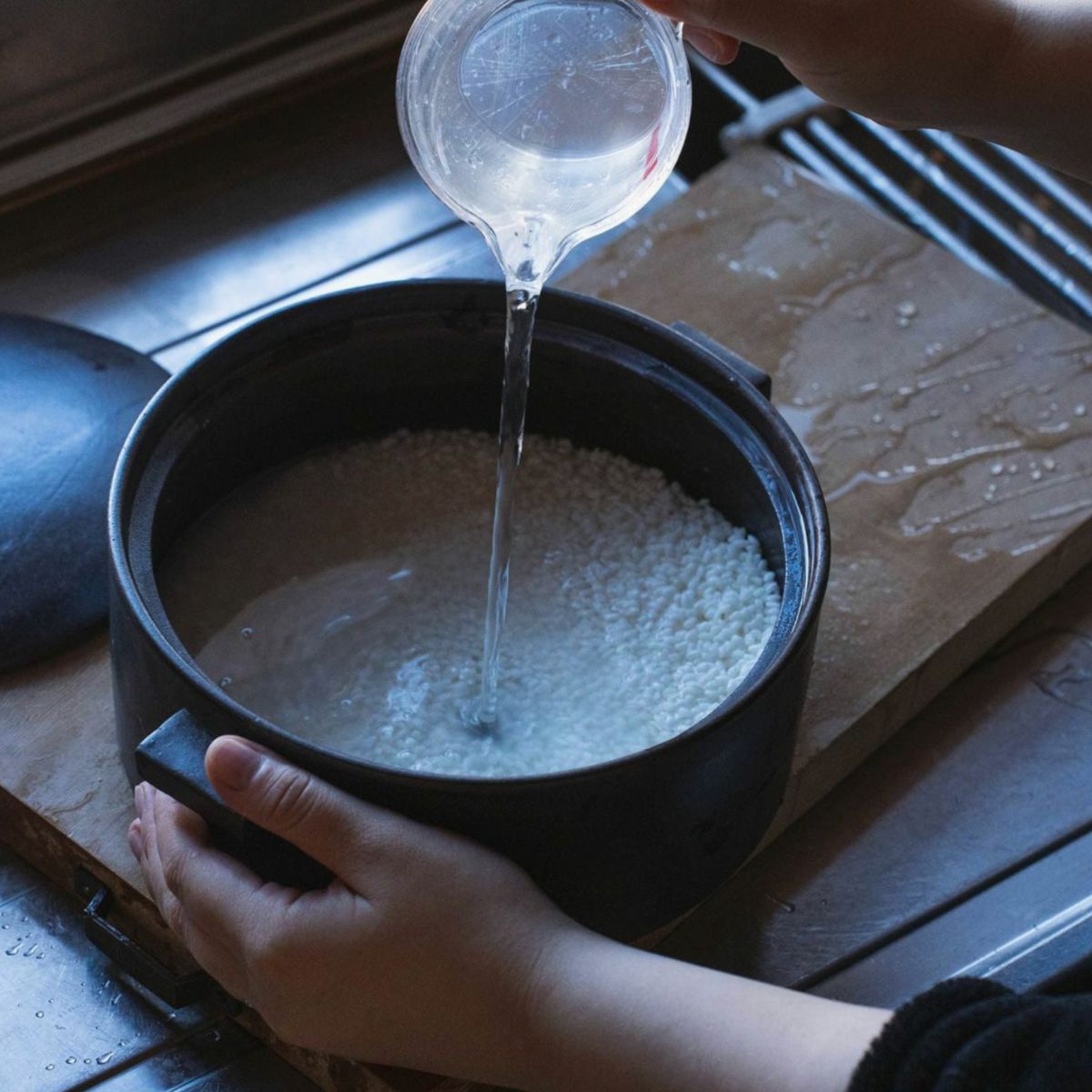 Japacolle Donabe – black Japanese ceramic rice cooking pot is filled with water, traditional preparation of rice.
