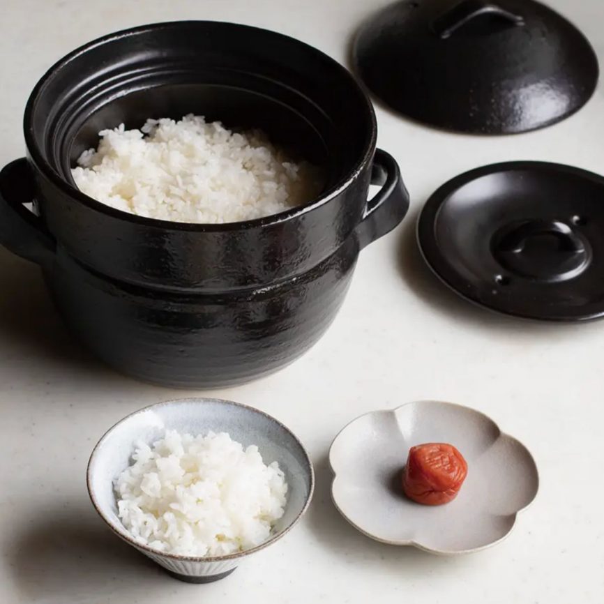 Japacolle Donabe – schwarzer japanischer Keramik-Reiskochtopf mit frisch gekochtem Reis, serviert in traditionellen Schalen.