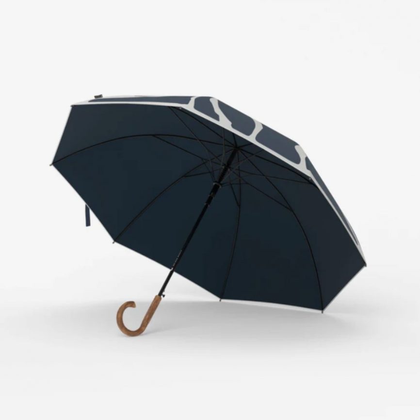 Liegeansicht eines Sapor Design Regenschirms mit abstraktem blau-weißem Muster und rotem Kreis auf dem Schirmdach.