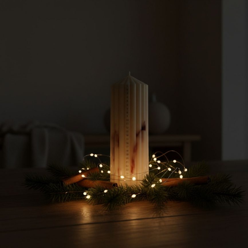 Studio M Candles Adventskerze mit Datumsskala, dekoriert mit Tannenzweigen, Zimtstangen und warmen Lichterketten in gemütlicher Abendstimmung.
